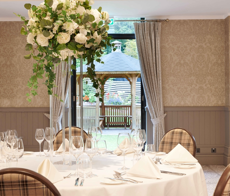 white table with chairs surrounding it and a large white floral arrangement and a gazebo outside an open door