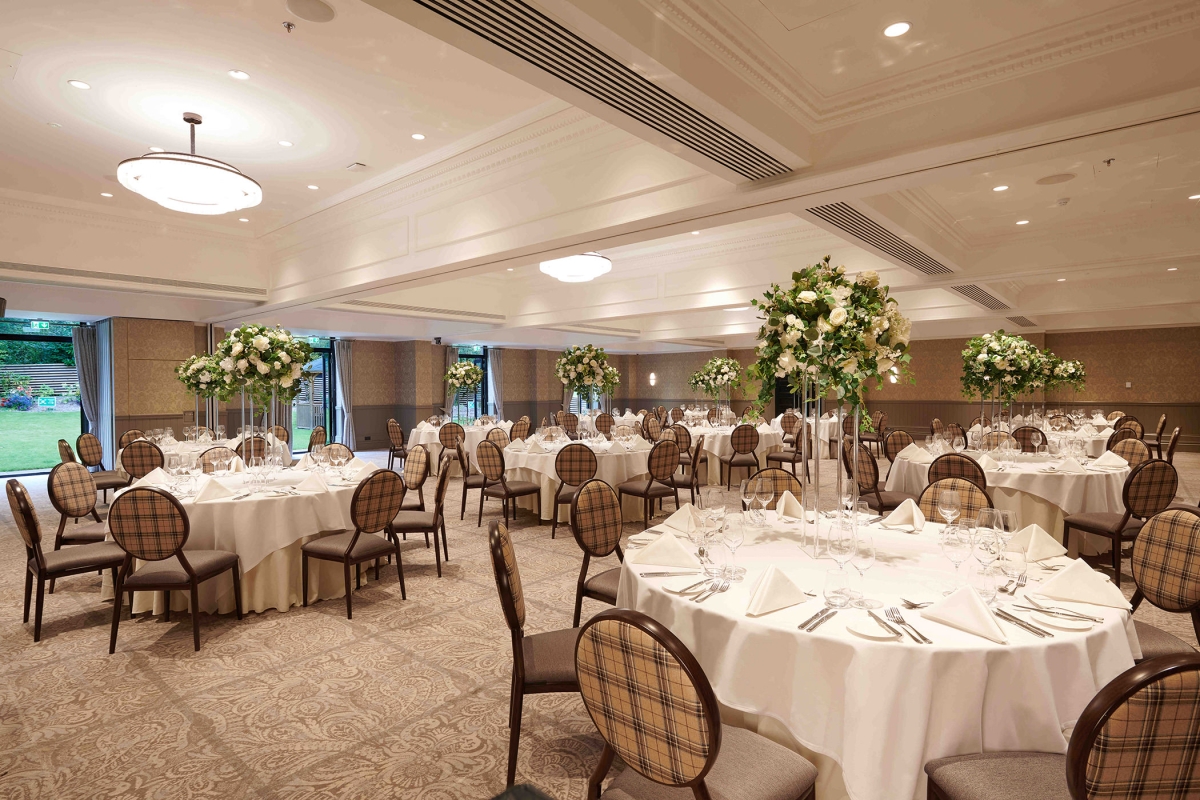 floral arrangements on top of tables with chairs around them inside a meeting area