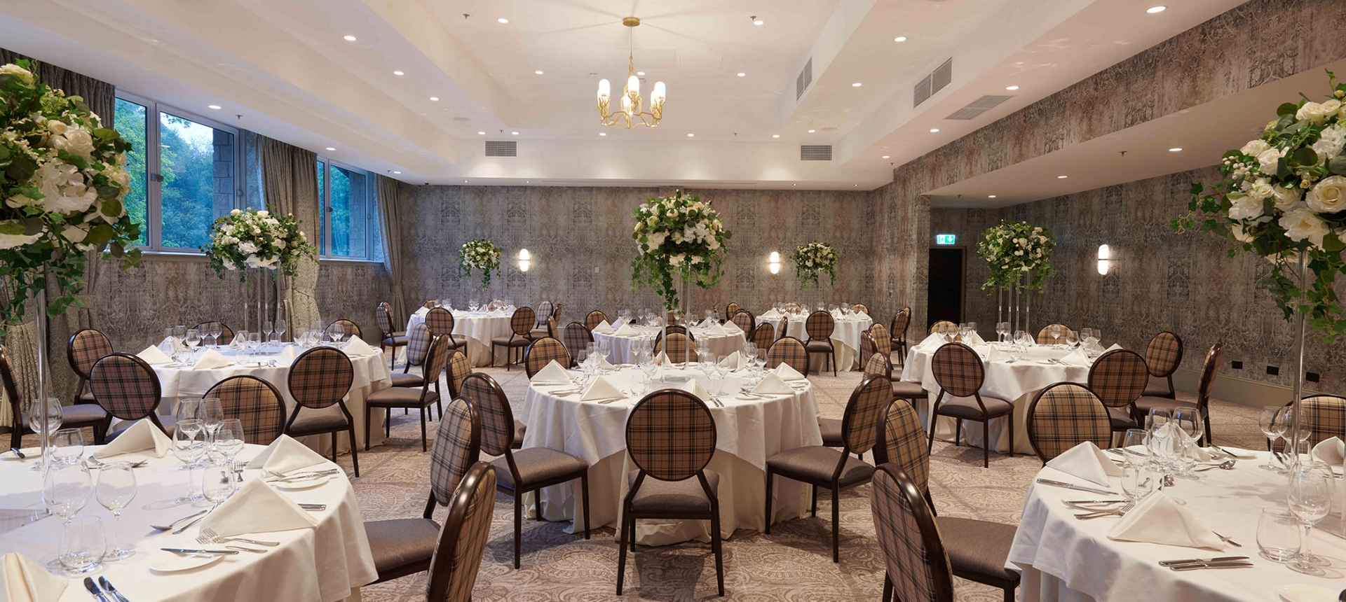elegant chair and table arrangements inside a weeding space with side windows to look outside