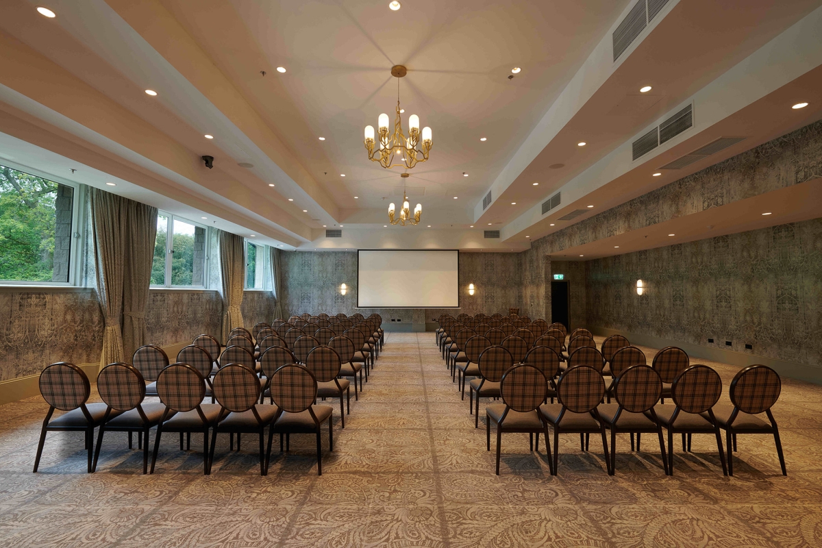 Meeting space inside Cameron House with rows of seating, large projector screen and channeller lighting