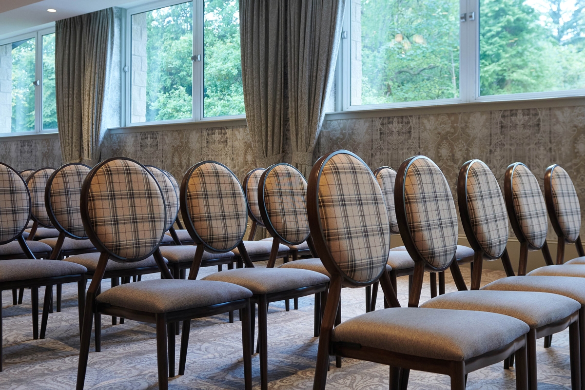 chairs set up inside a event space with views of the outside trees