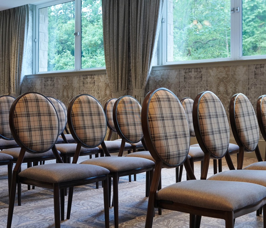 chairs set up inside a event space with views of the outside trees