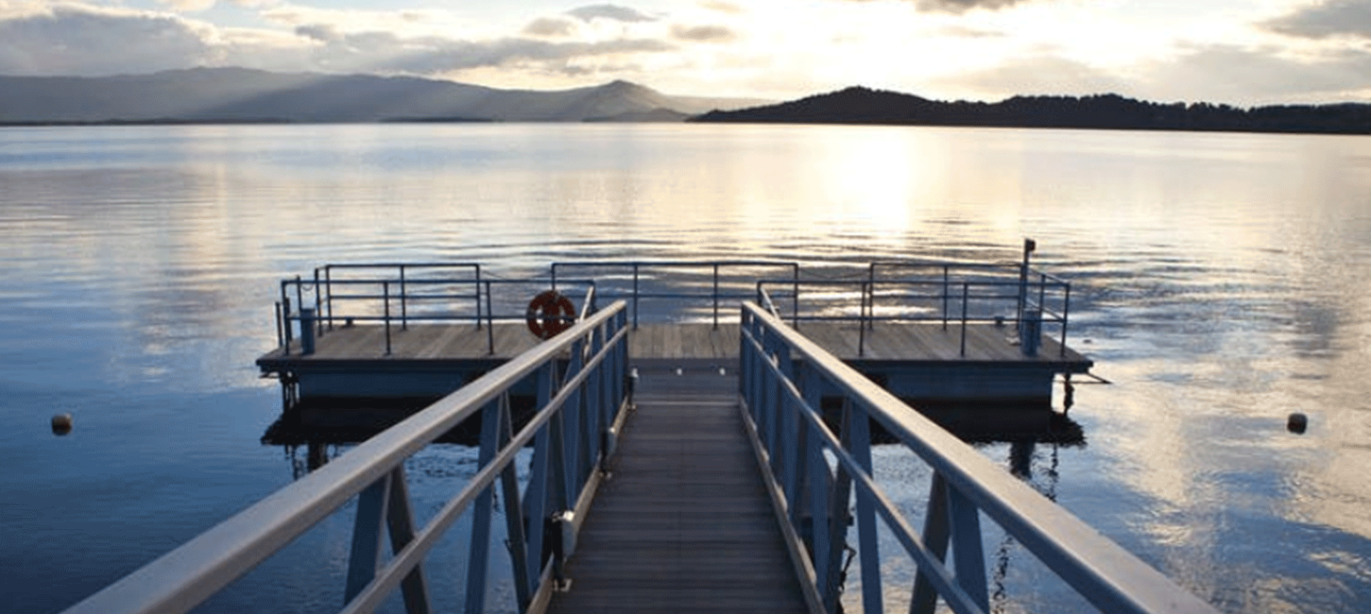a dock sitting on a body of water with mountains in the back