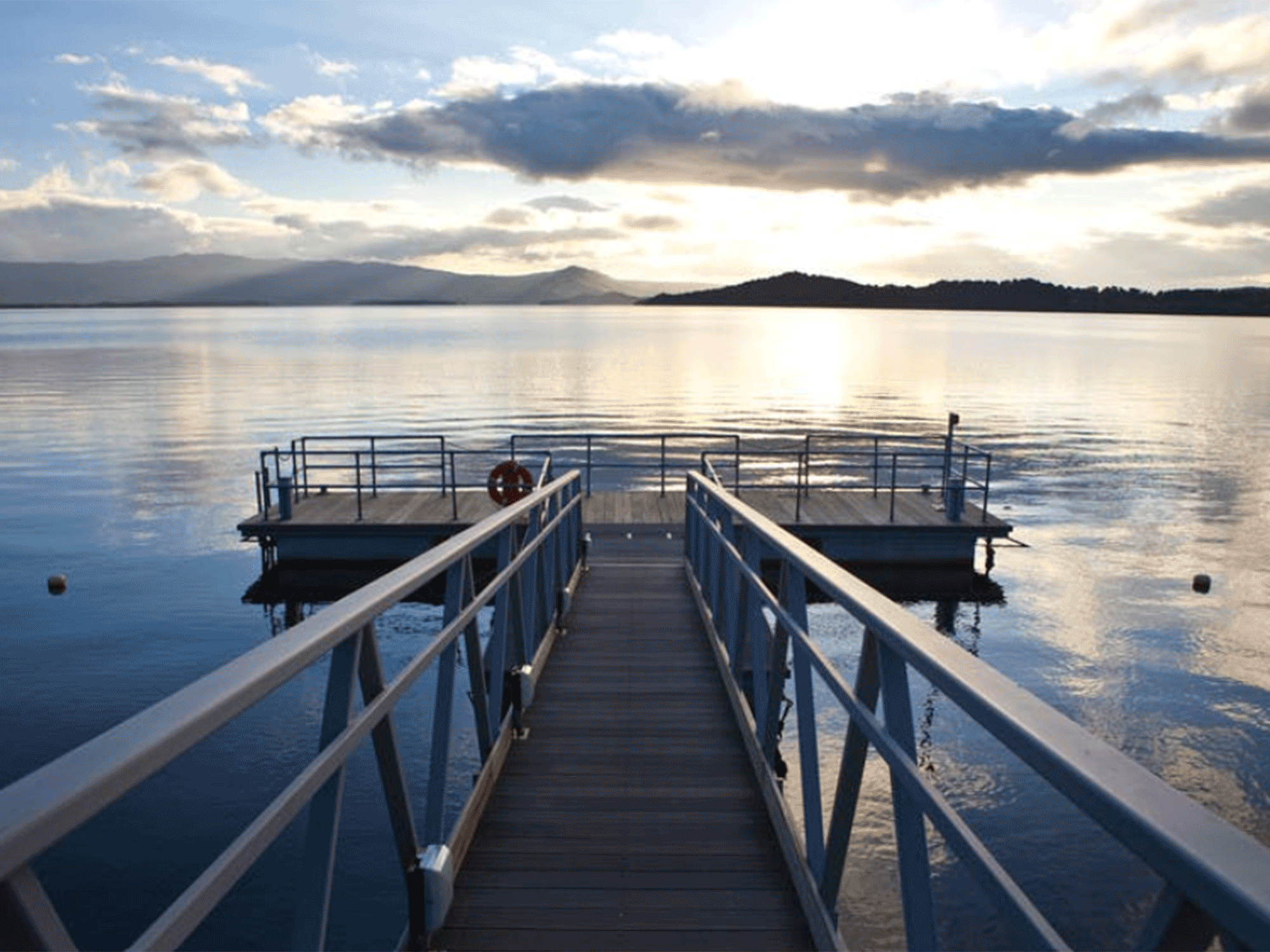 a dock sitting on a body of water with mountains in the back