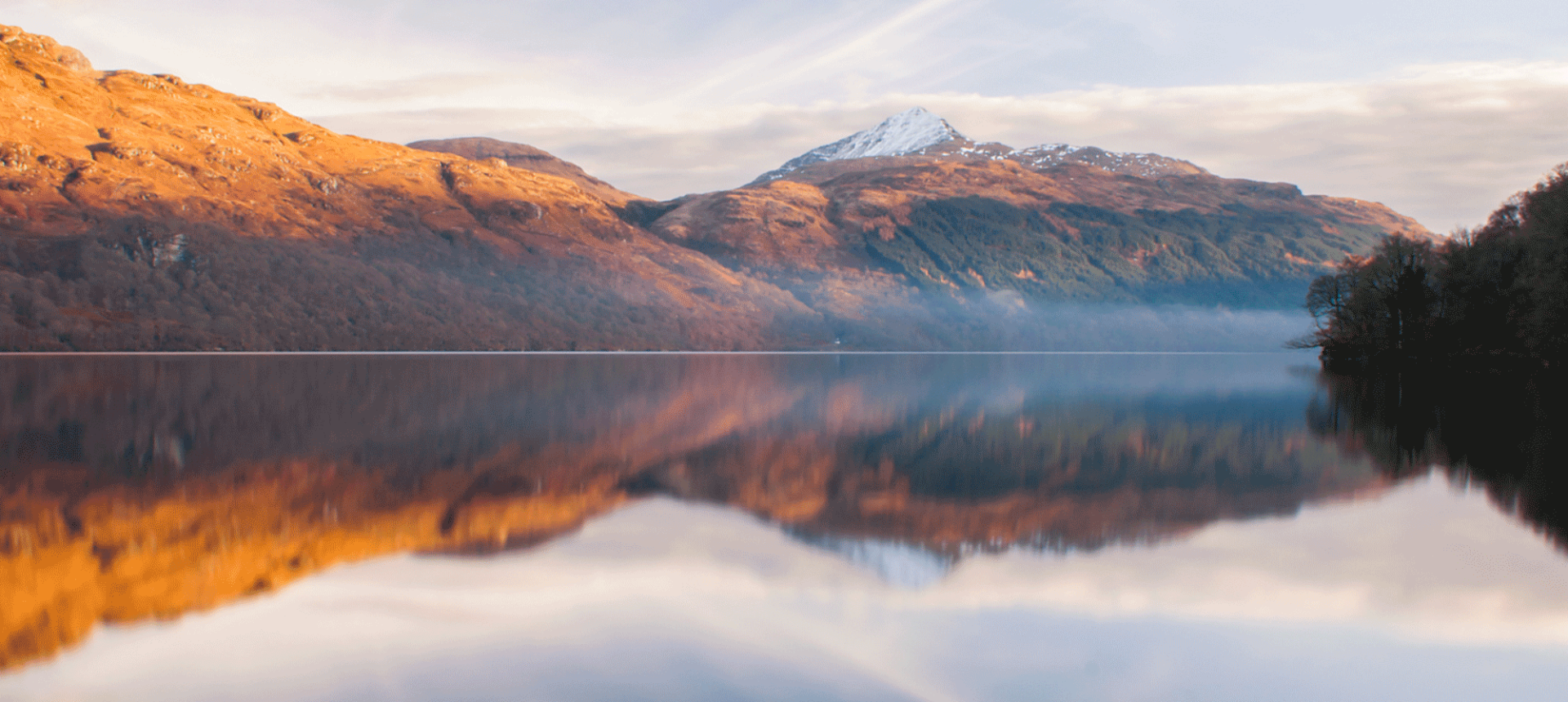 a picture taken from the edge of water showing some large mountains in the back