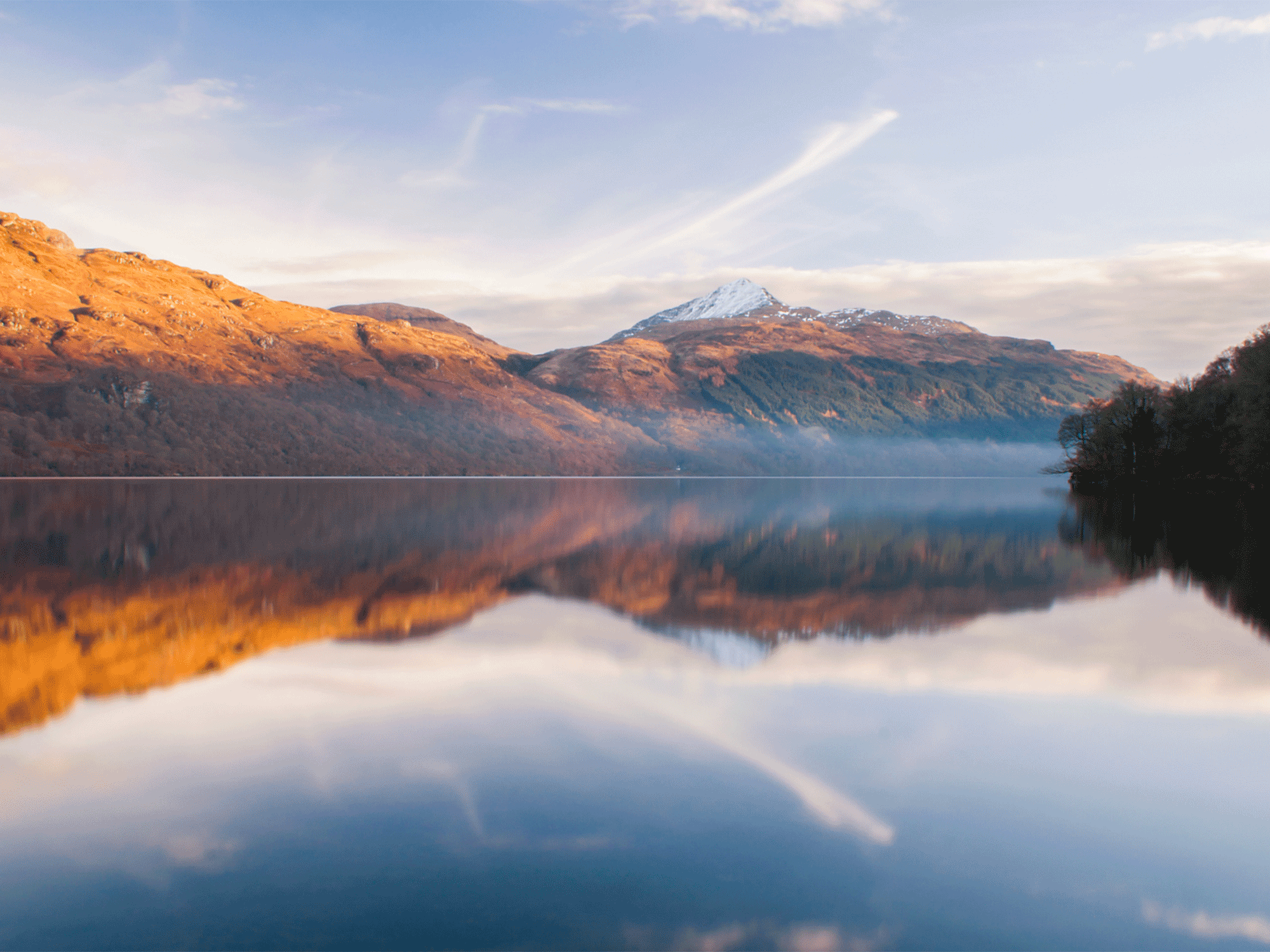 a picture taken from the edge of water showing some large mountains in the back
