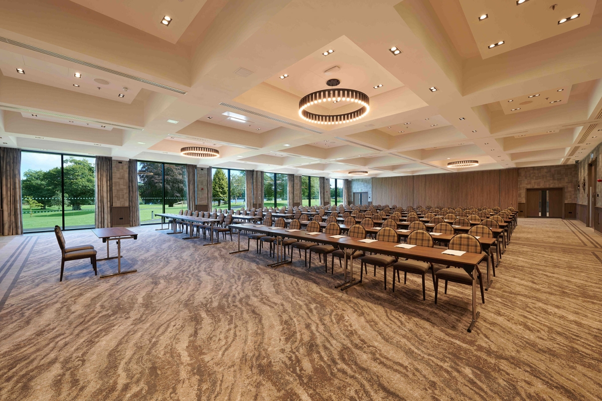 Meeting room with rows of tables and chairs and a gorgeous outside view with bright green trees