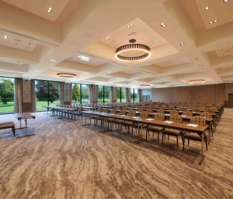 Meeting room with rows of tables and chairs and a gorgeous outside view with bright green trees