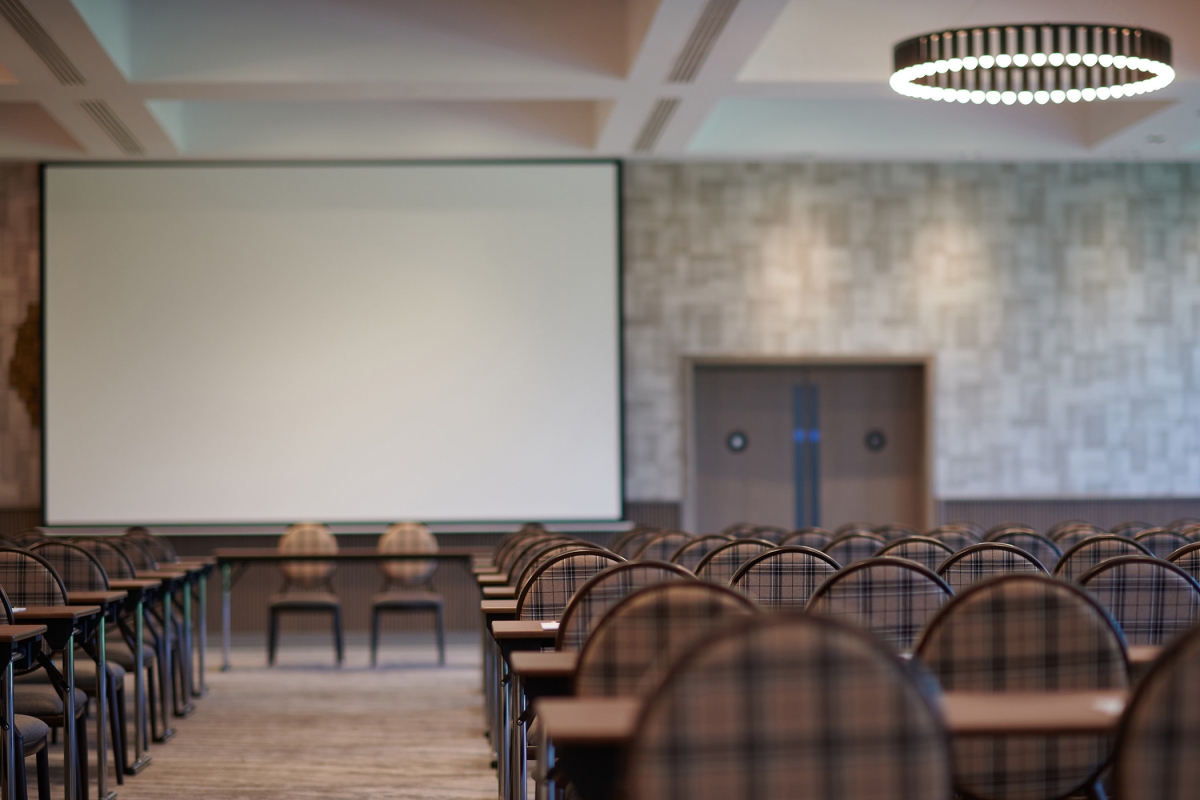 meeting space with tables and chairs in the room along with a large projector