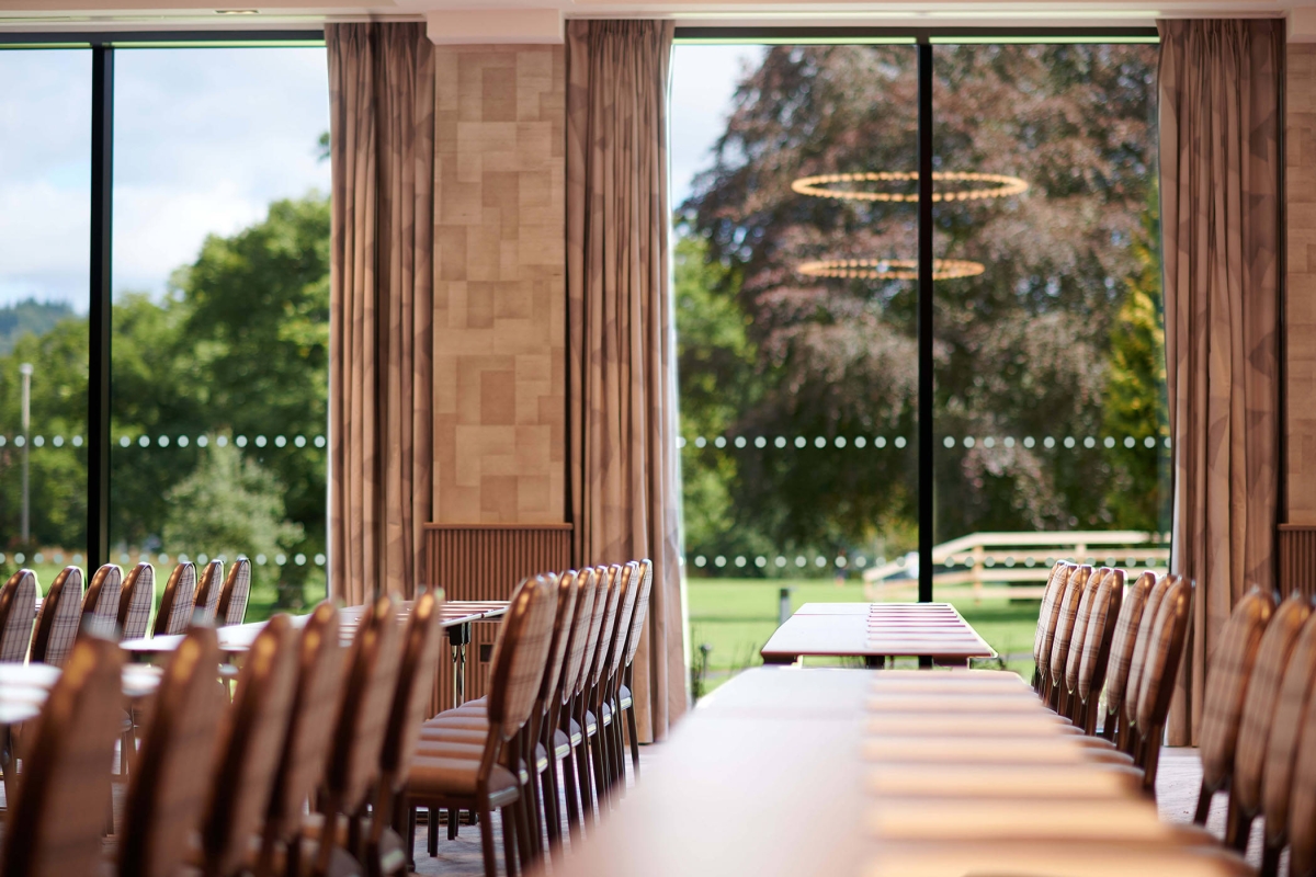 tables and chairs inside a room and large clear windows giving a view outside