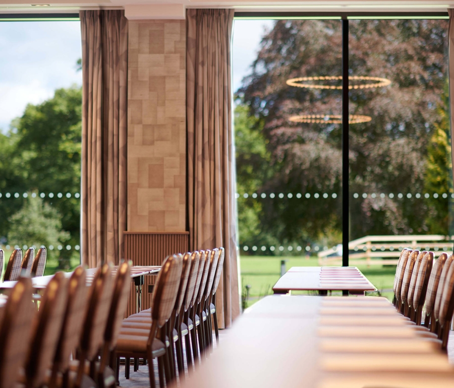 tables and chairs inside a room and large clear windows giving a view outside