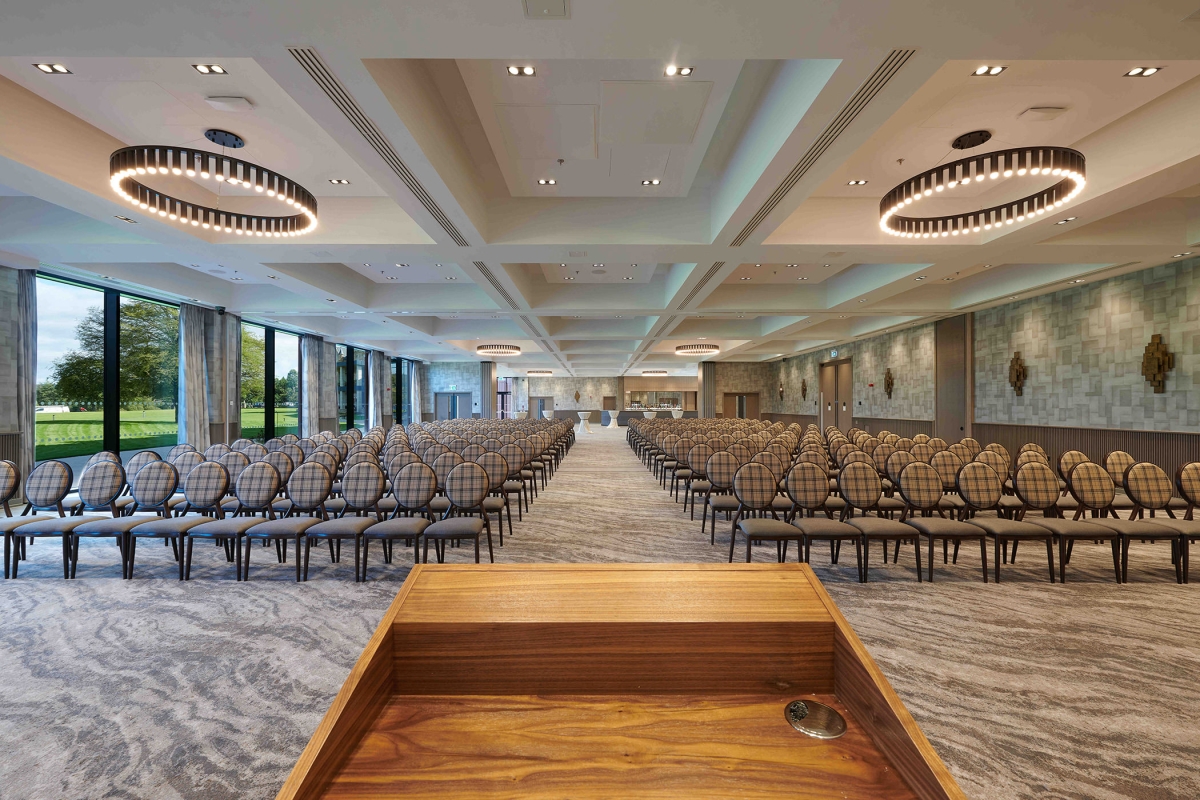 podium overlooking a endless view of chairs and a bar in the back corner of the room