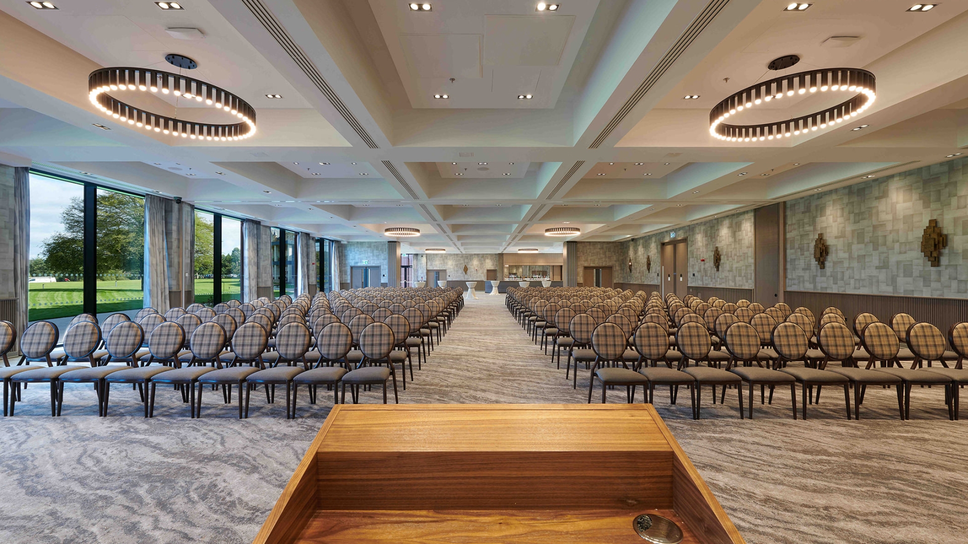 podium overlooking a endless view of chairs and a bar in the back corner of the room