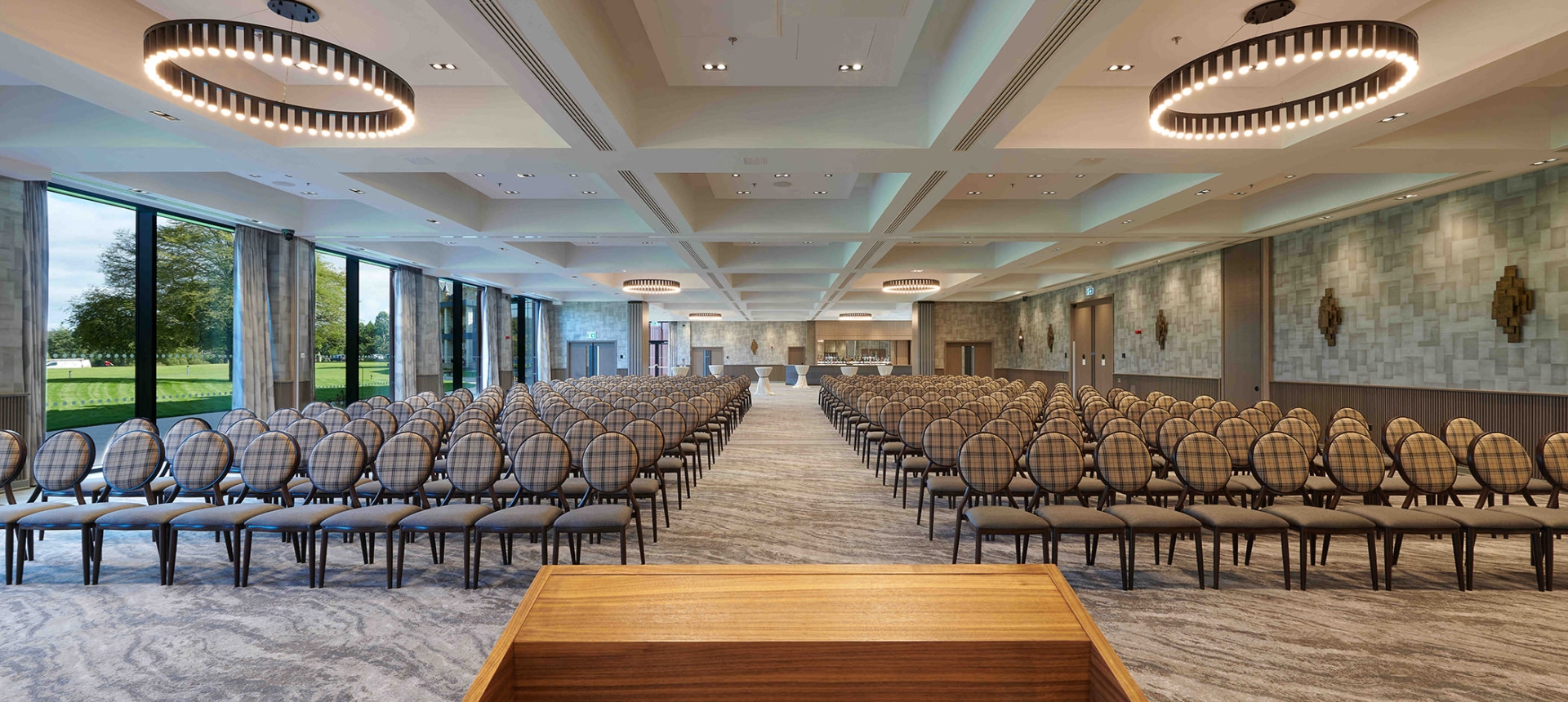 podium overlooking a endless view of chairs and a bar in the back corner of the room