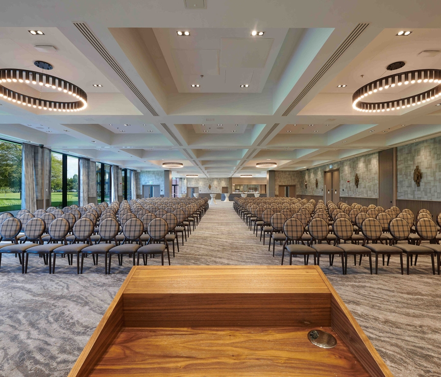 podium overlooking a endless view of chairs and a bar in the back corner of the room