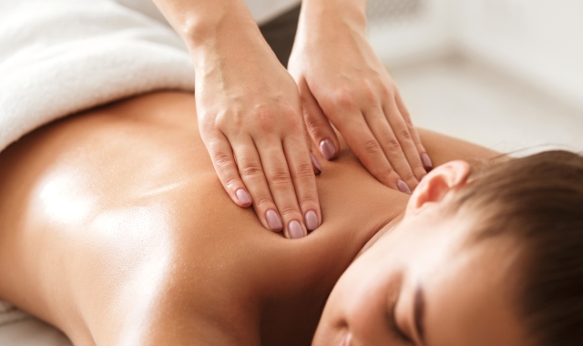 a woman laying face down on a table while getting her back massaged