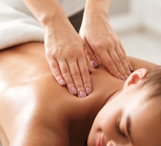 a woman laying face down on a table while getting her back massaged