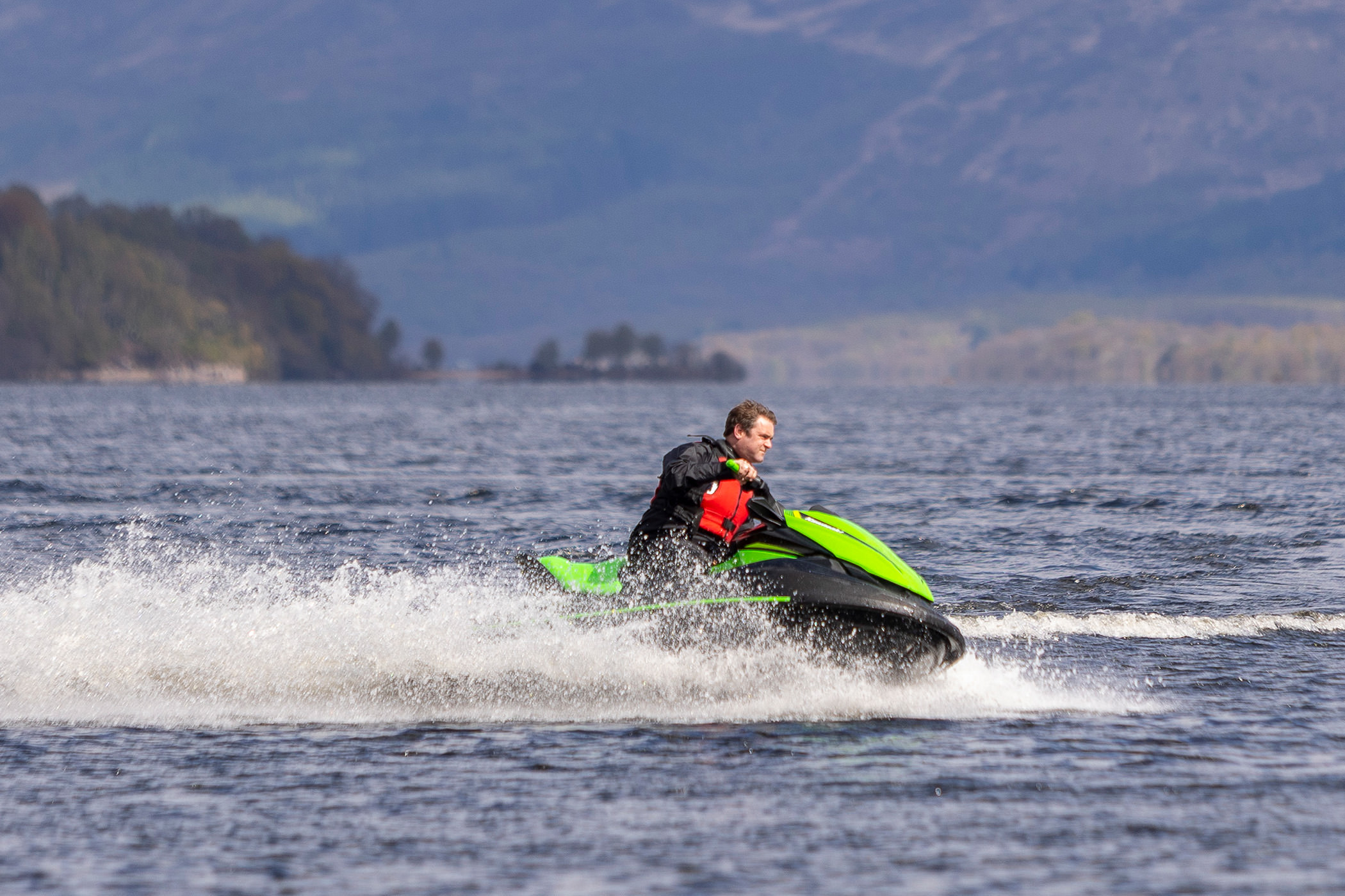 a man riding a bright green and black jet ski on the water