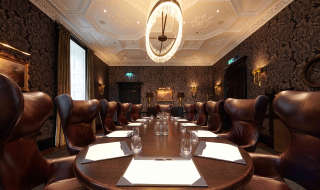 conference meeting space with a large round table and many brown leather chairs
