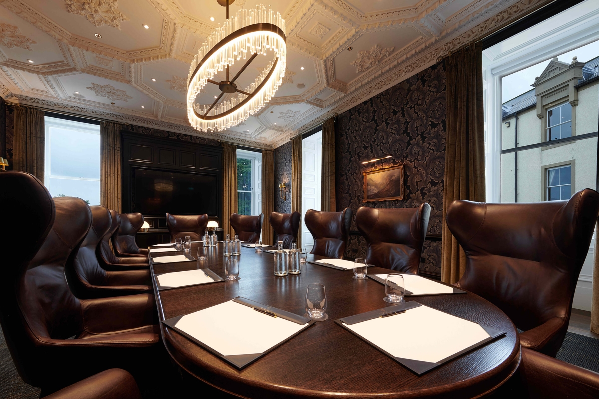 Large oval table and brown chairs with windows looking outside to the exterior of the building