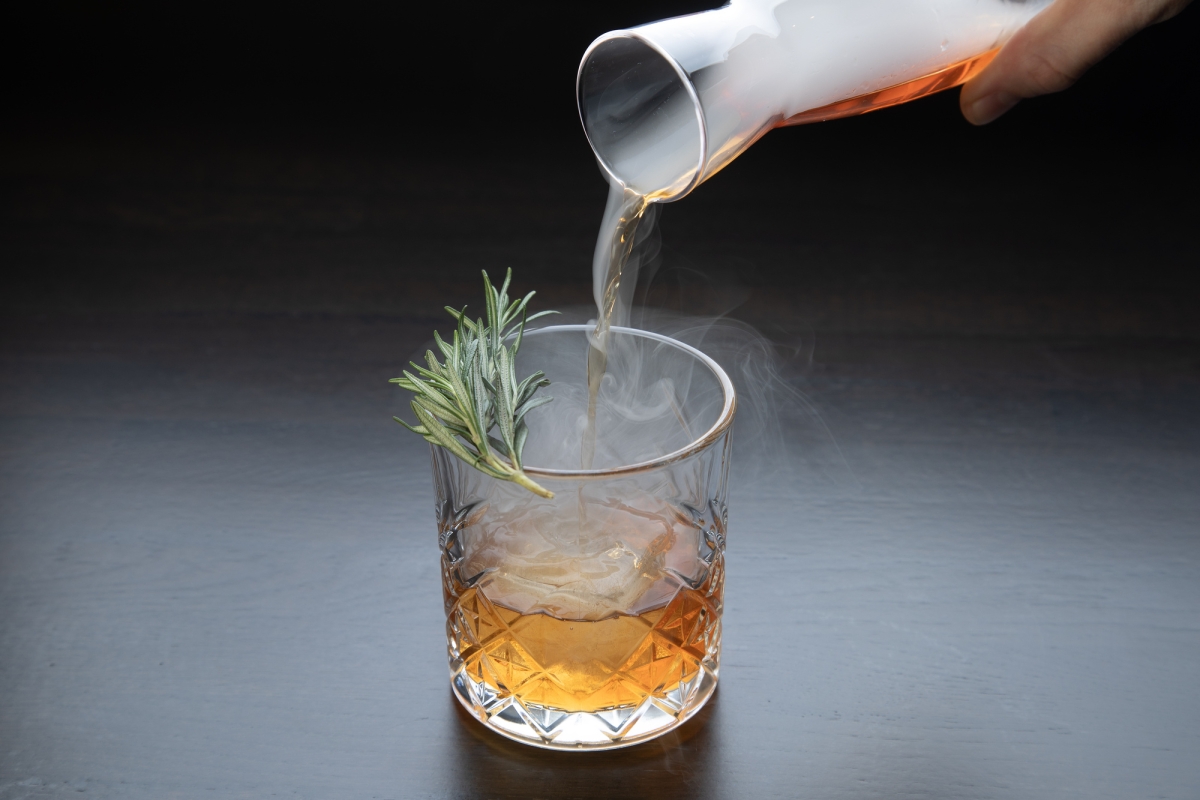 A person pouring a negroni cocktail into a glass at La Vista restaurant.