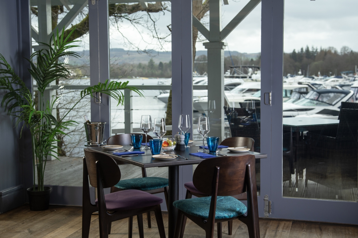 A window view of the marina with a table and four chairs at La Vista restaurant.