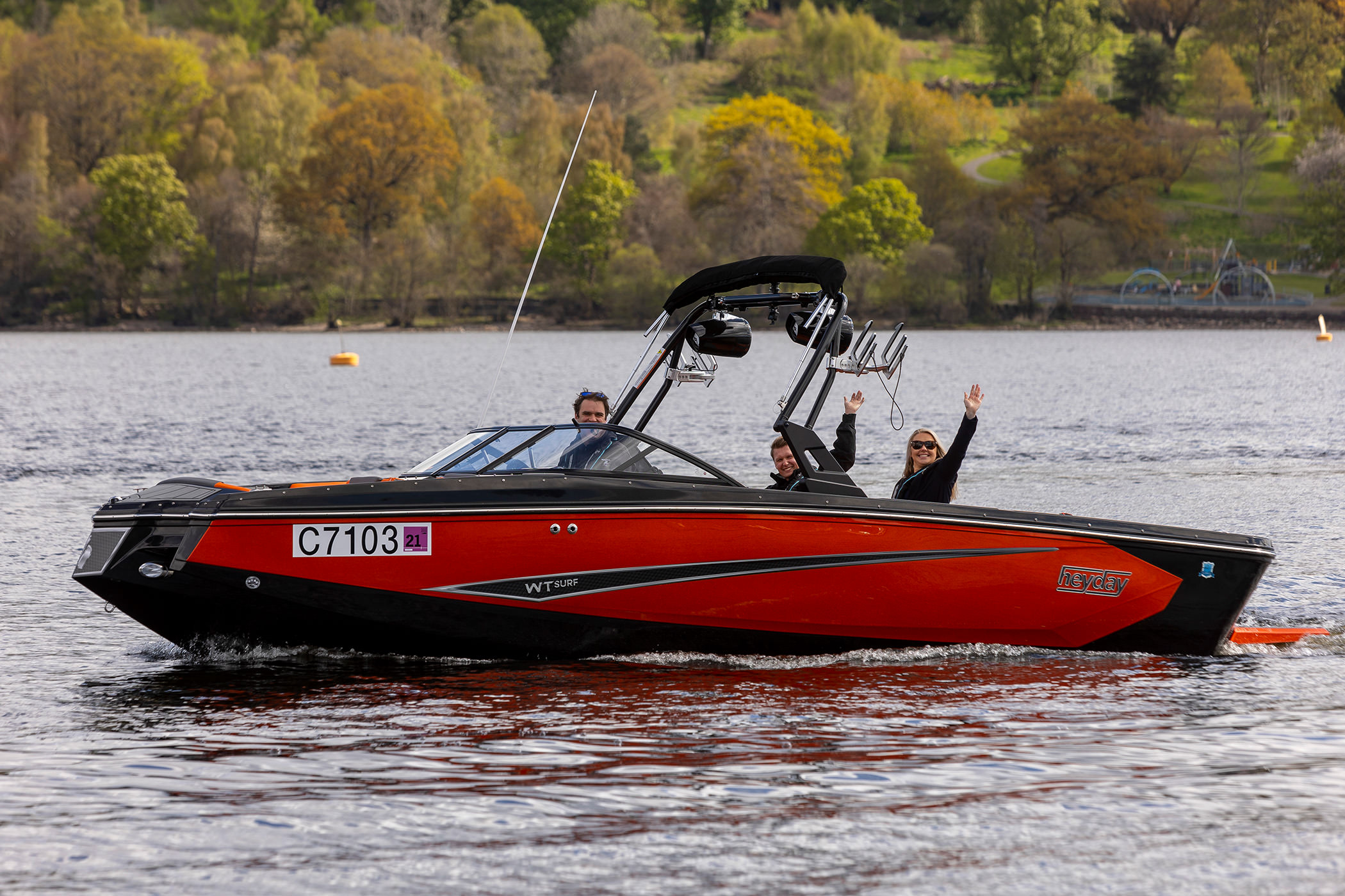three people riding on a boat in the water waving to the camera