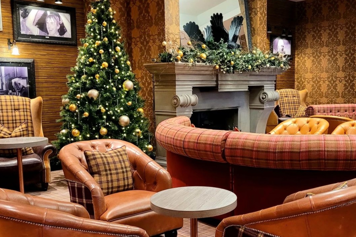 Lounge area with cozy fireplace, comfortable couches, and a festive Christmas tree.