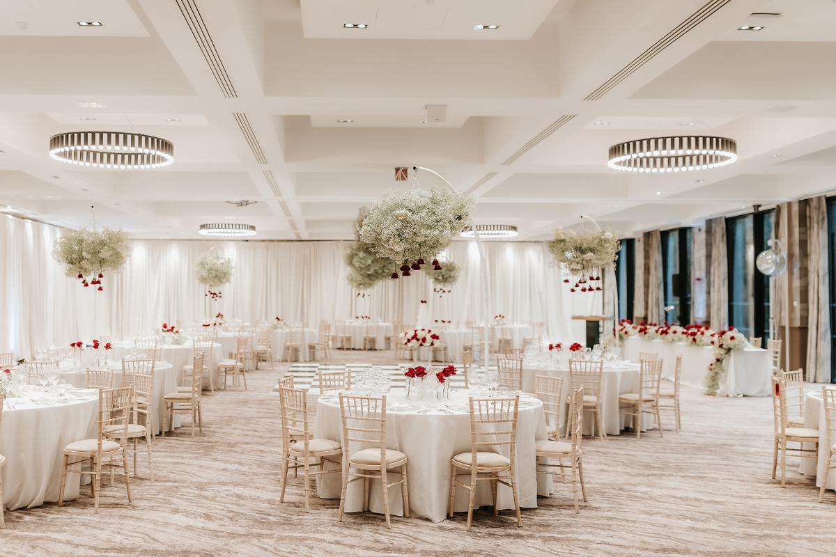 large dining room with white tables and chairs along with hanging flower arrangements over the table tops