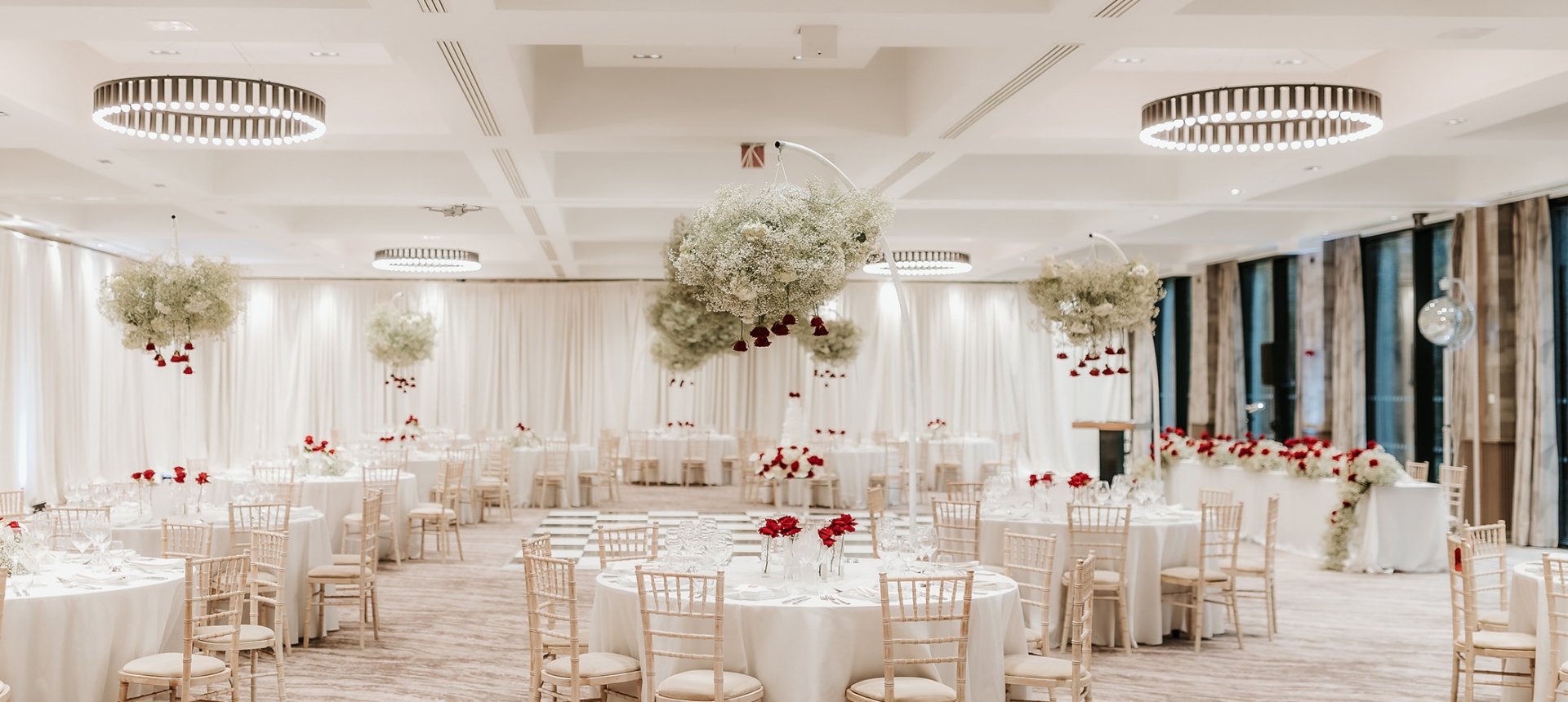 large dining room with white tables and chairs along with hanging flower arrangements over the table tops