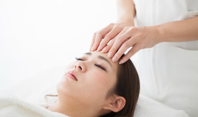 a woman laying on a table getting her forehead massaged