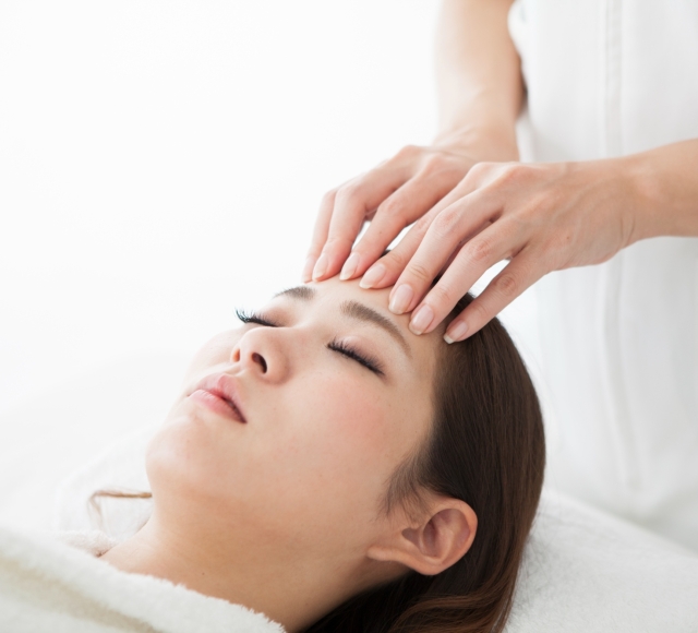 a woman laying on a table getting her forehead massaged