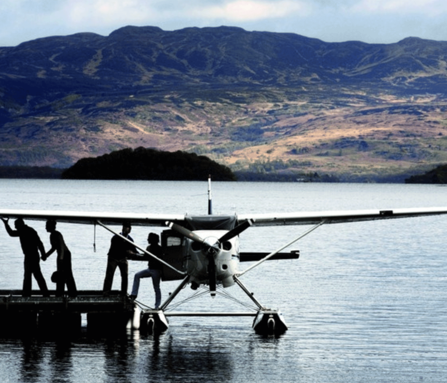 people exiting a sea plane that has landed on the water next to a dock