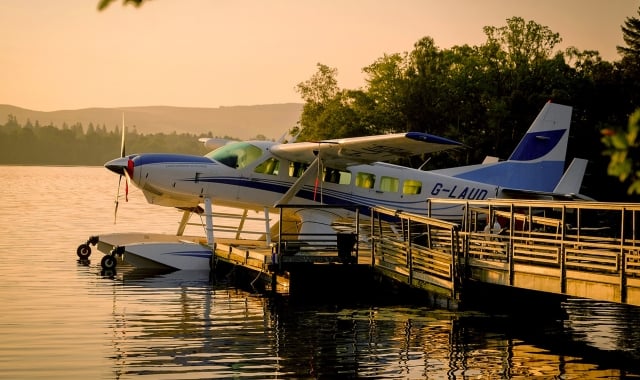 blue and white plane sitting on the water during sun set