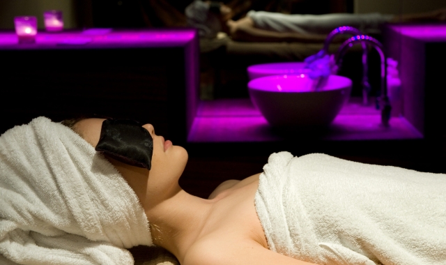 a woman sitting in a spa relaxing with a large mirror showing her reflection