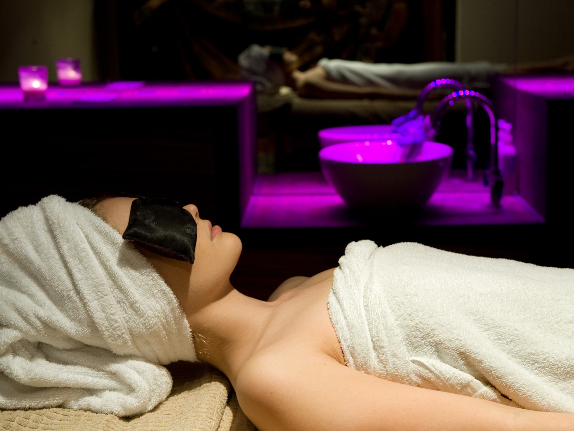 a woman sitting in a spa relaxing with a large mirror showing her reflection