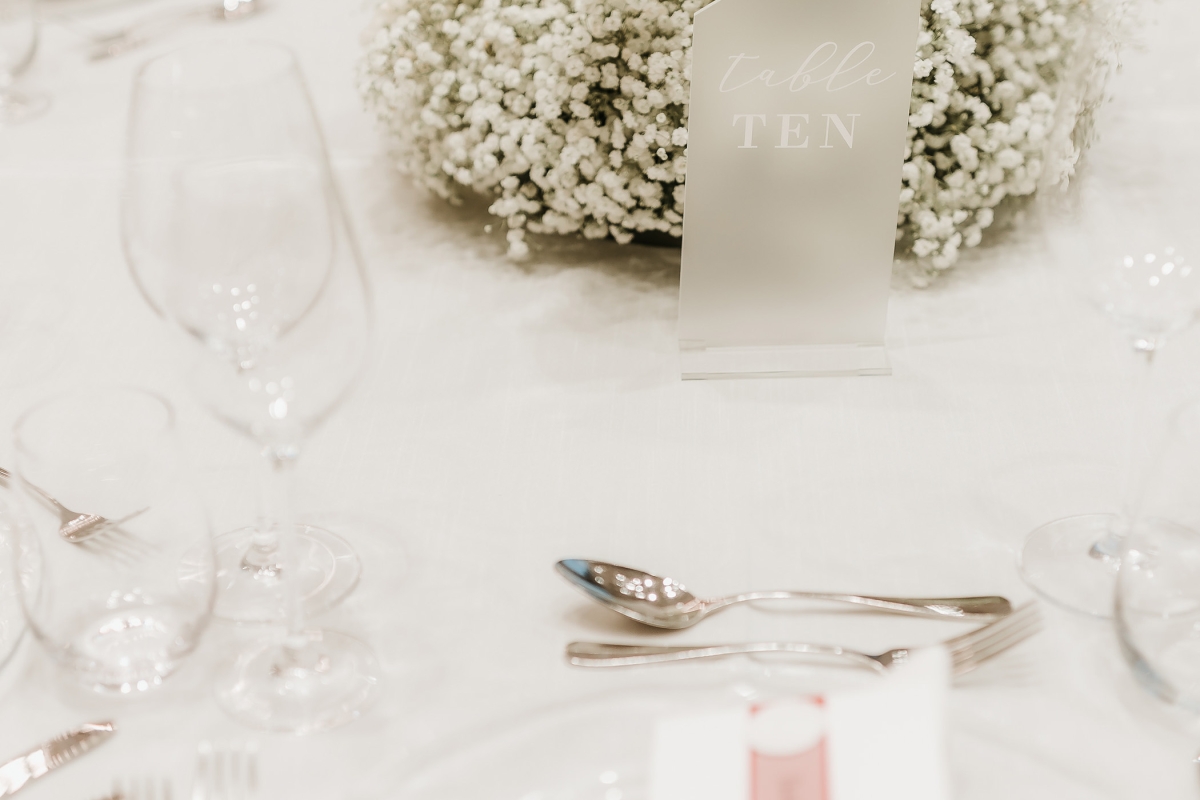 dining table set up with silverware along with roses in the center of the table