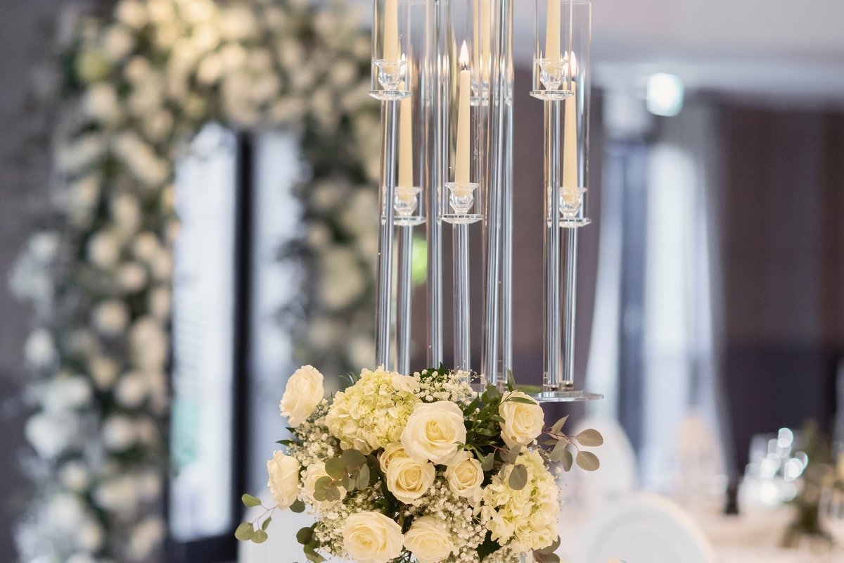 a floral arrangement set up with candles in the center of a white table