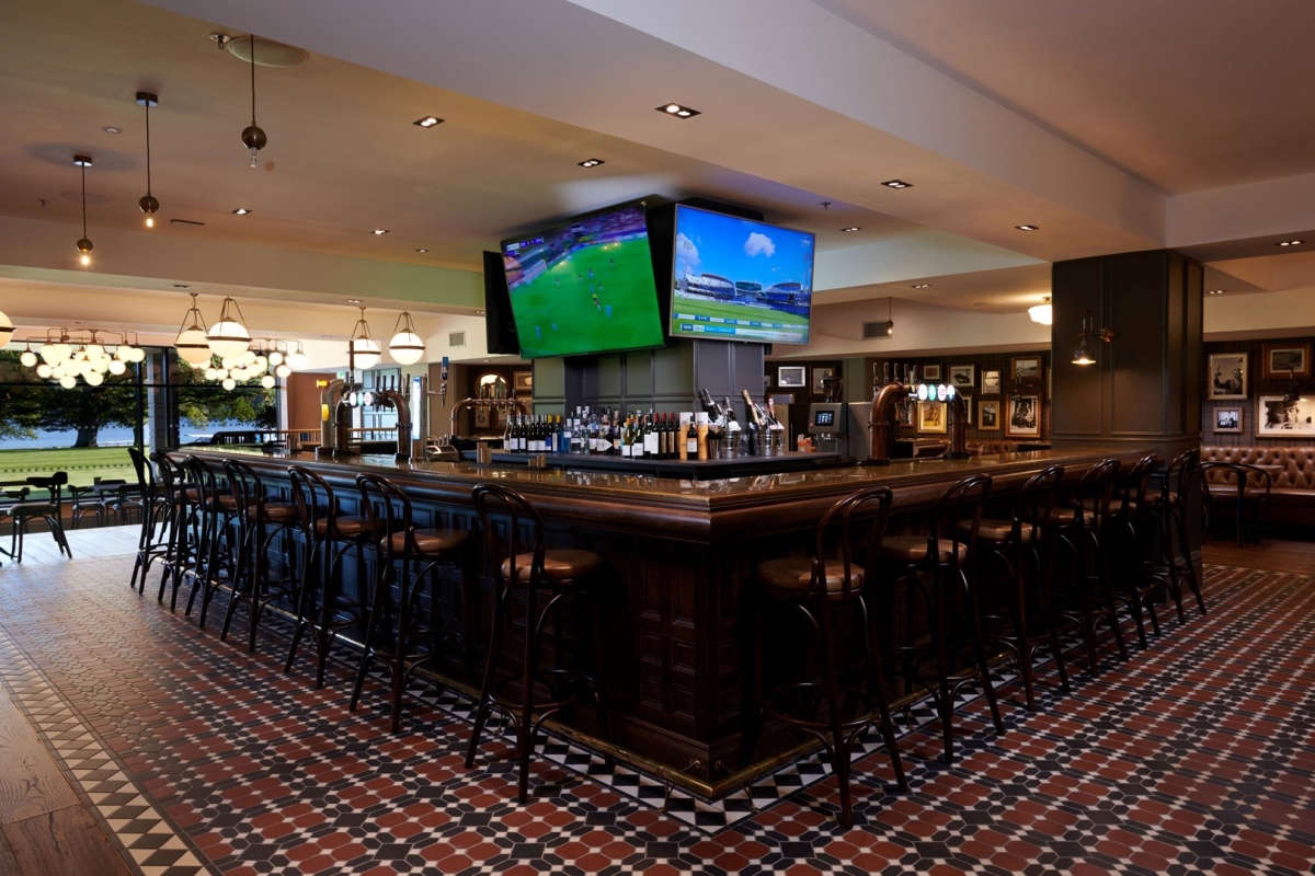 a bar space with seating around it and sports on the tv's in the background