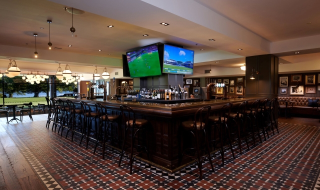 a bar space with seating around it and sports on the tv's in the background