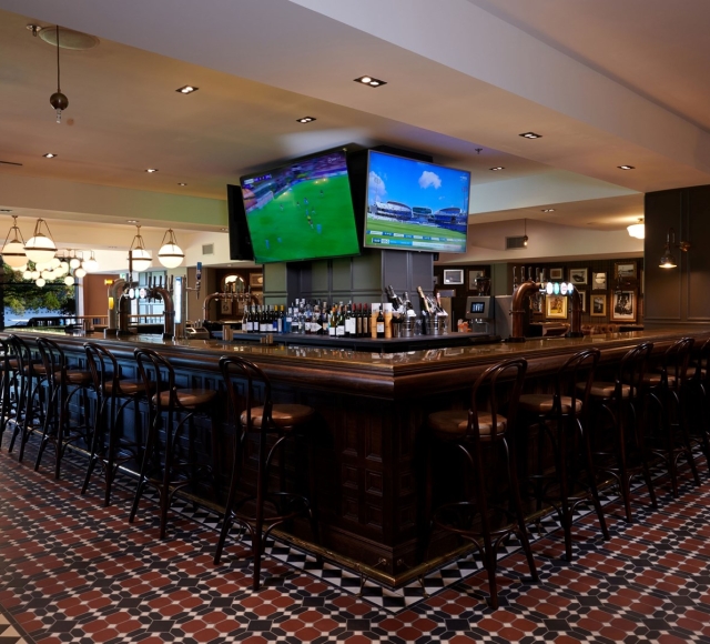 a bar space with seating around it and sports on the tv's in the background