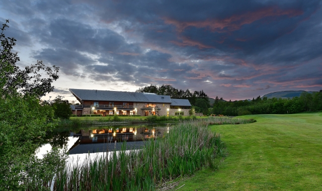 a small lake with a building behind it on a cloudy night