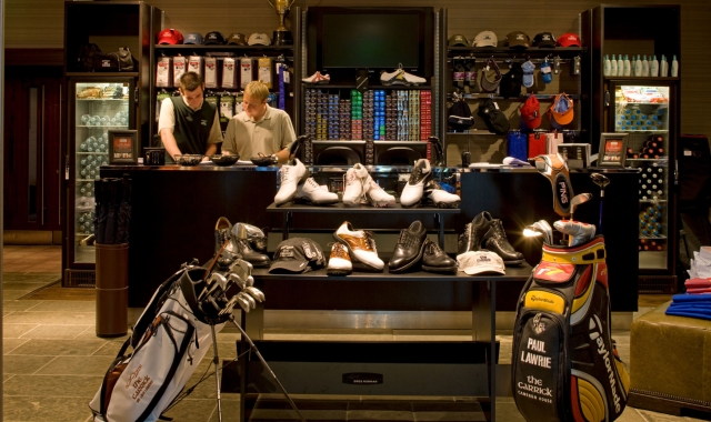 an in door golf equipment shop with two workers standing behind the counter