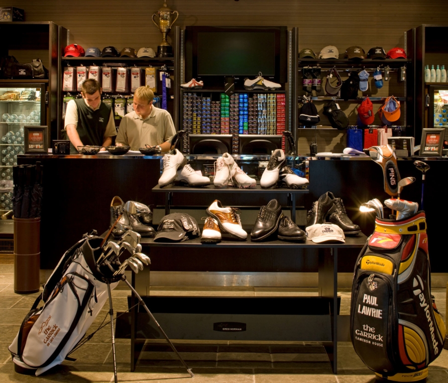 an in door golf equipment shop with two workers standing behind the counter