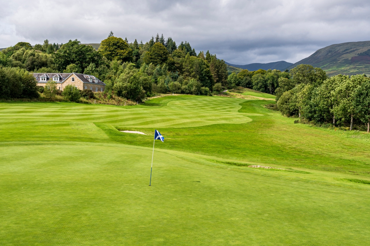 golf course with wide open field and buildings in the background