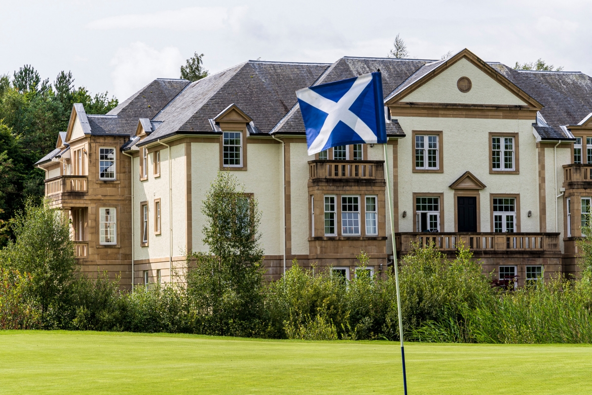 close up view of a gold course hole with a blue and white flag sticking up