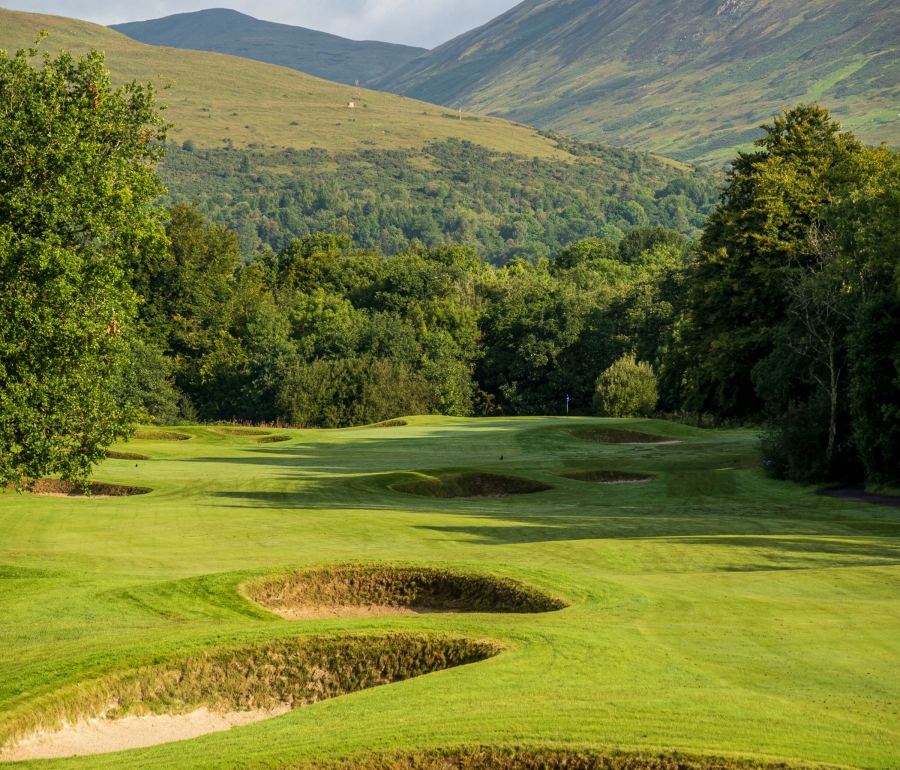 a golf course with sand pits and mountains in the back ground