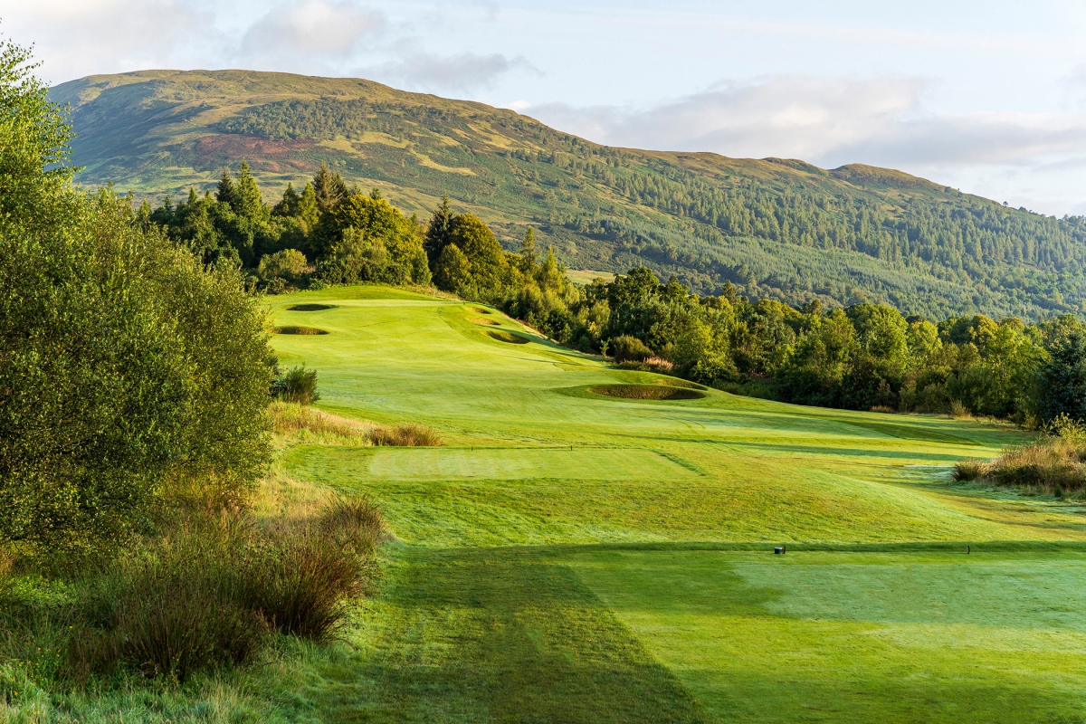 golf course with large sand pits surrounded by mountains and trees