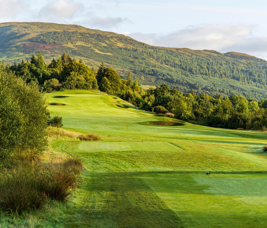 golf course with large sand pits surrounded by mountains and trees