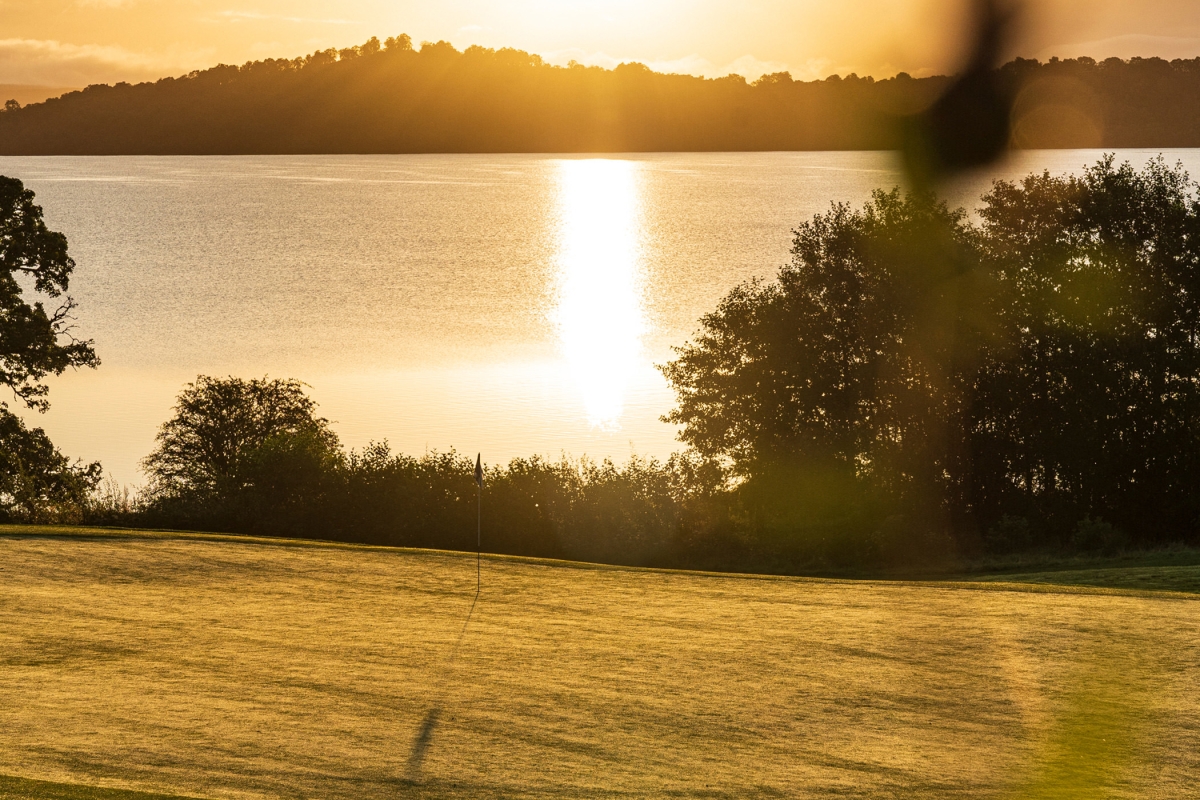 view of a golf course at sun set over looking the water